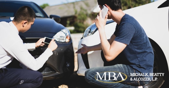 two men talking and taking pictures of their car accident