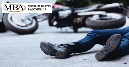 closeup of feet of someone lying on the ground with a motorcycle crash on the background